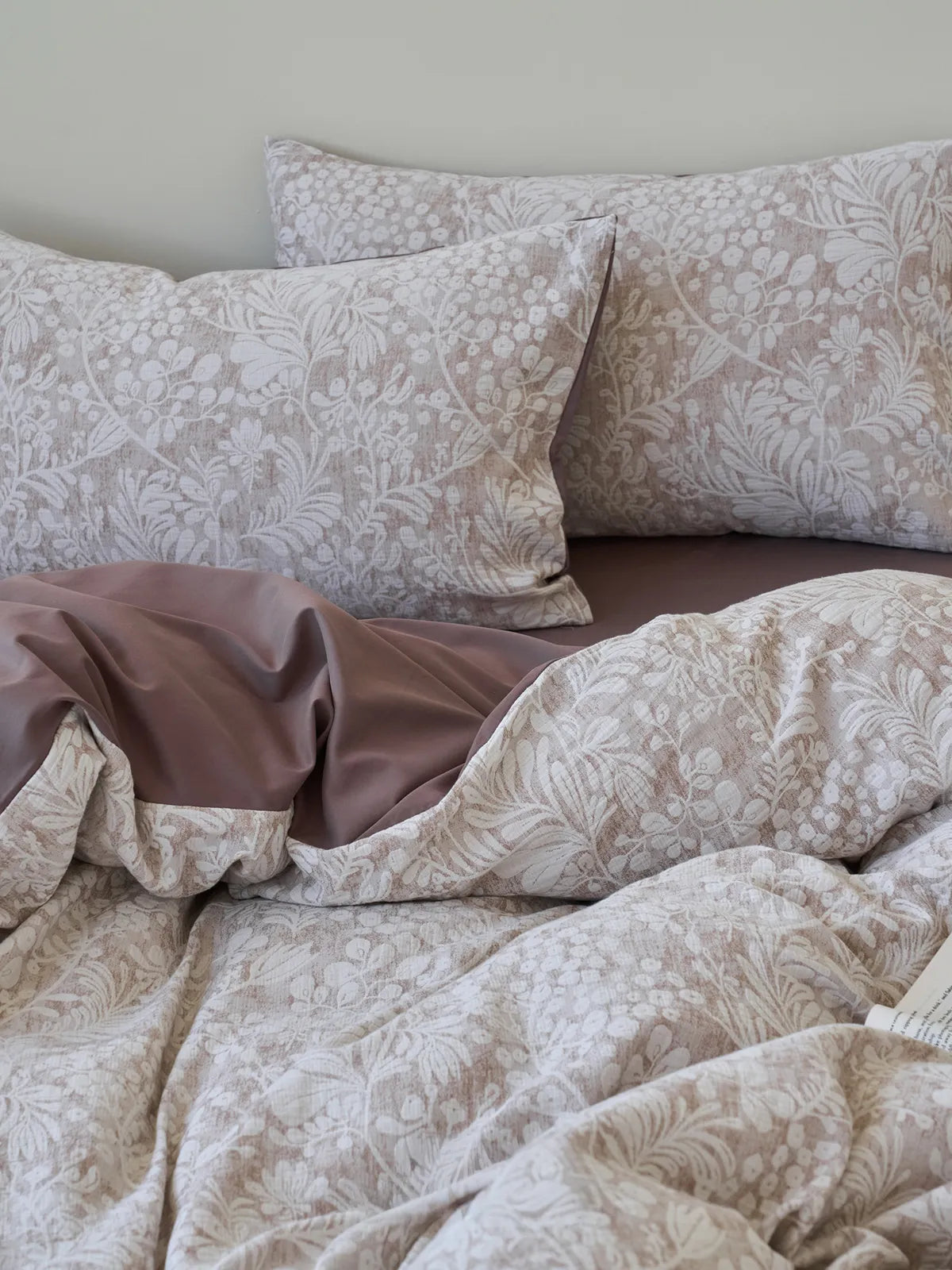 Close up of taupe and white botanical floral pillowcases and duvet cover texture RoomDen.