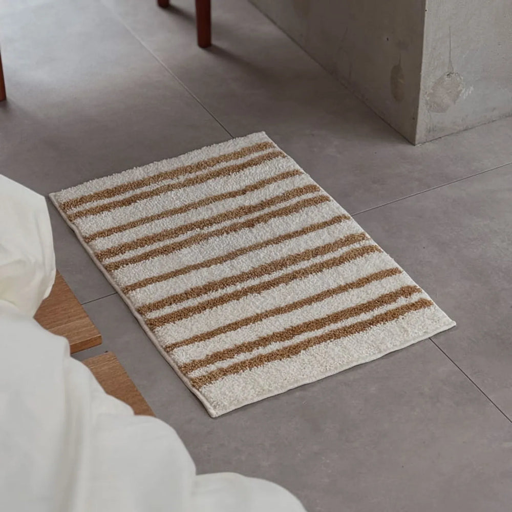 High-angle view of caramel and cream striped shaggy rug on grey tile floor - RoomDen