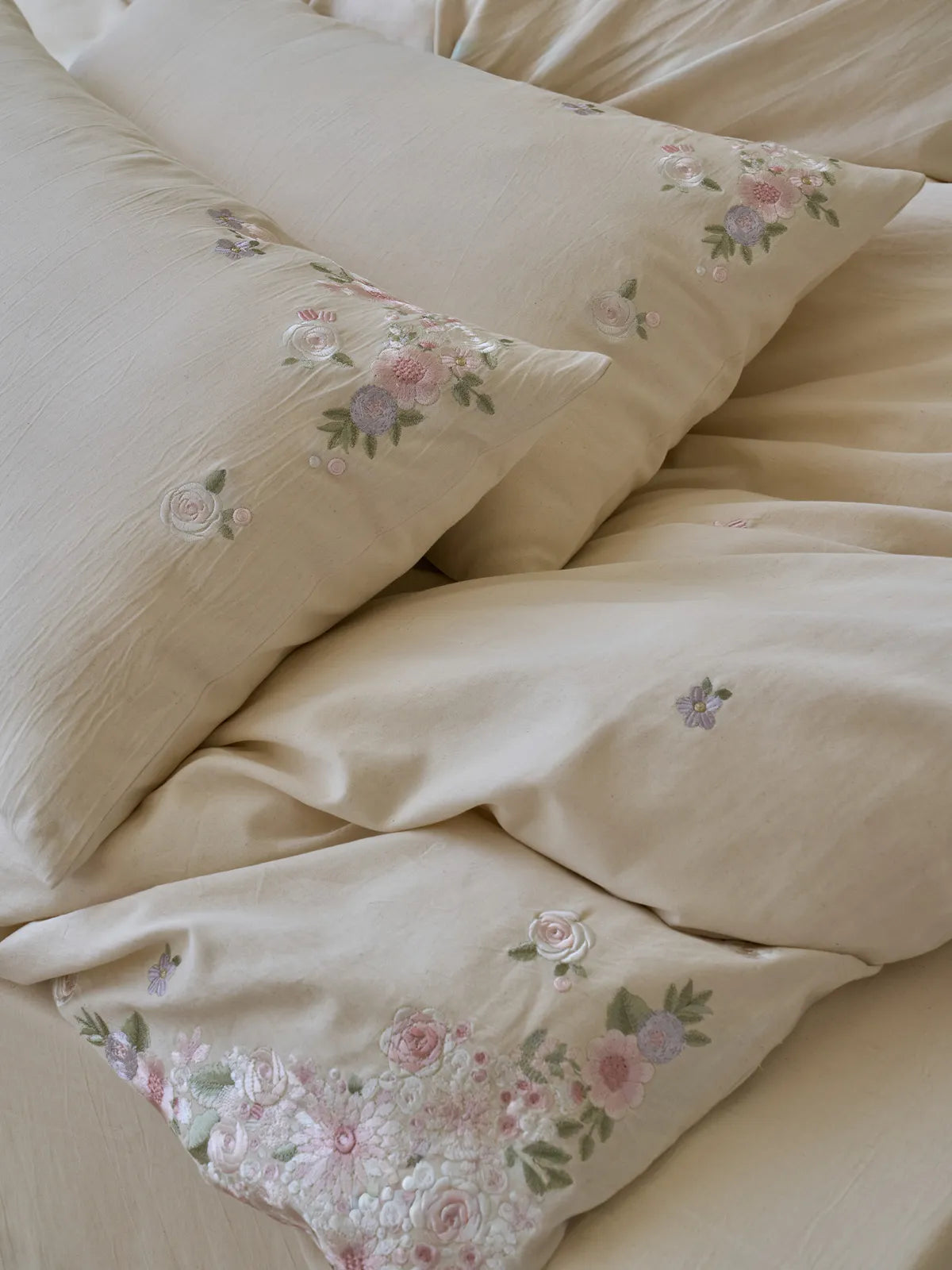 Close up of embroidered wildflowers on linen pillowcase with pom-pom trim by RoomDen.