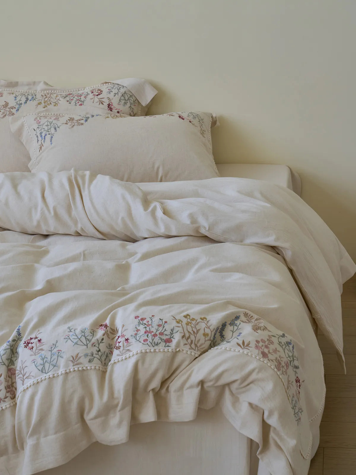 Full view of Wildflower Embroidered Linen duvet cover set on bed, cream color.