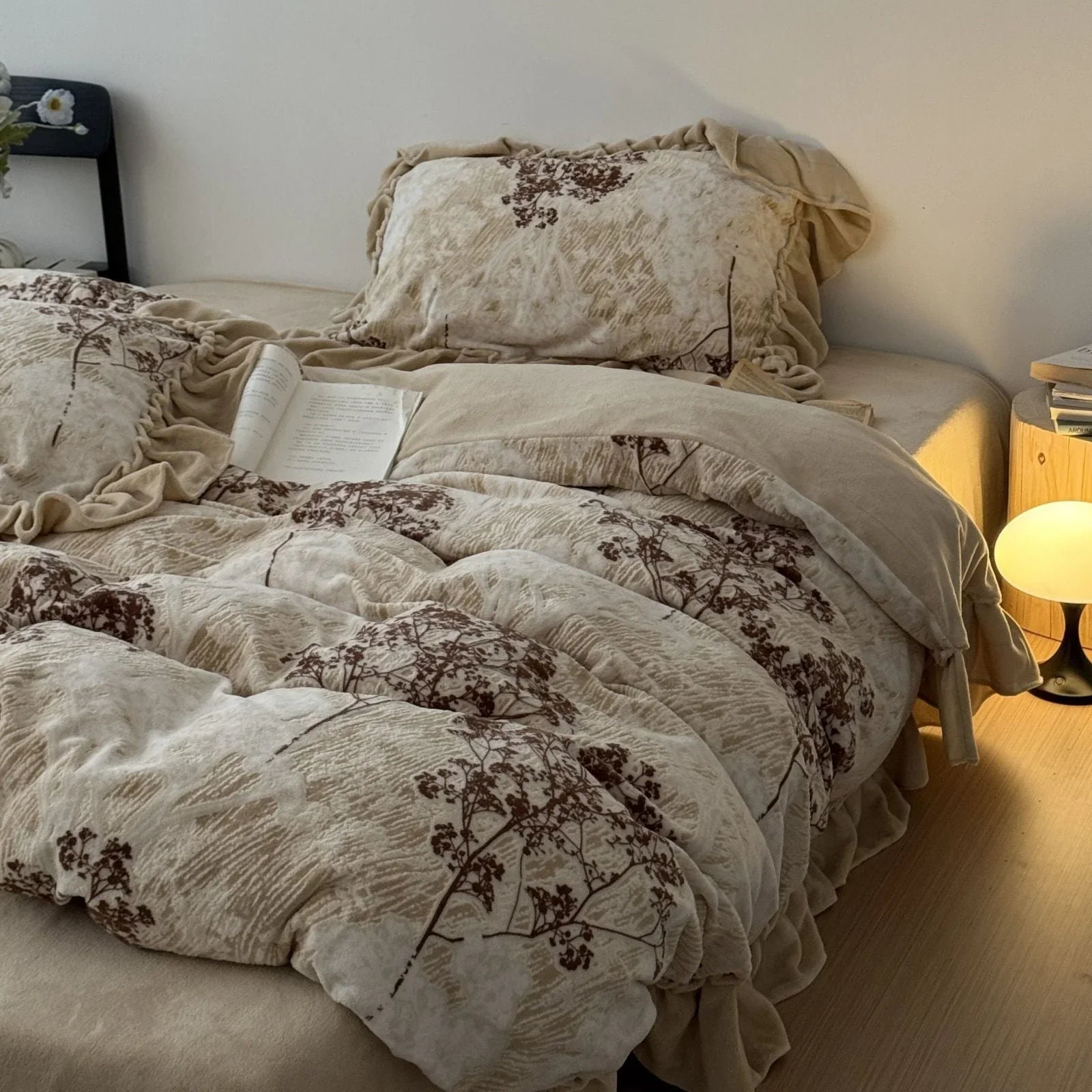 Cottagecore bedding — a ruffled vintage floral branch washed cotton set styled on a cozy bed with warm lamplight and an open book