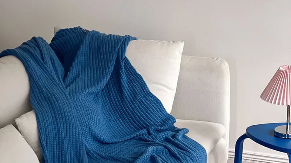 Luxurious velvet blanket and throw pillows used to add cozy texture and layering to a sofa or foot of the bed.