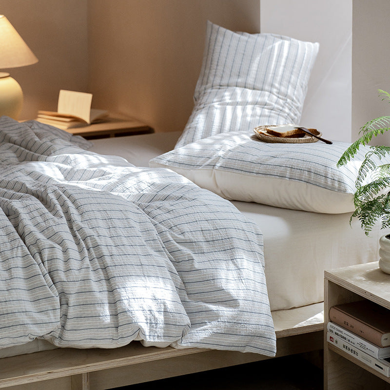 Winslet Pinstripe Cotton Bedding Set – side view of the striped duvet beside a warm bedside lamp - Roomden