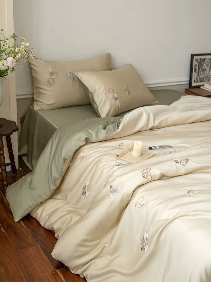 Butterfly embroidered lyocell bedding – Full bed view with a green sheet and embroidered pillows - Roomden