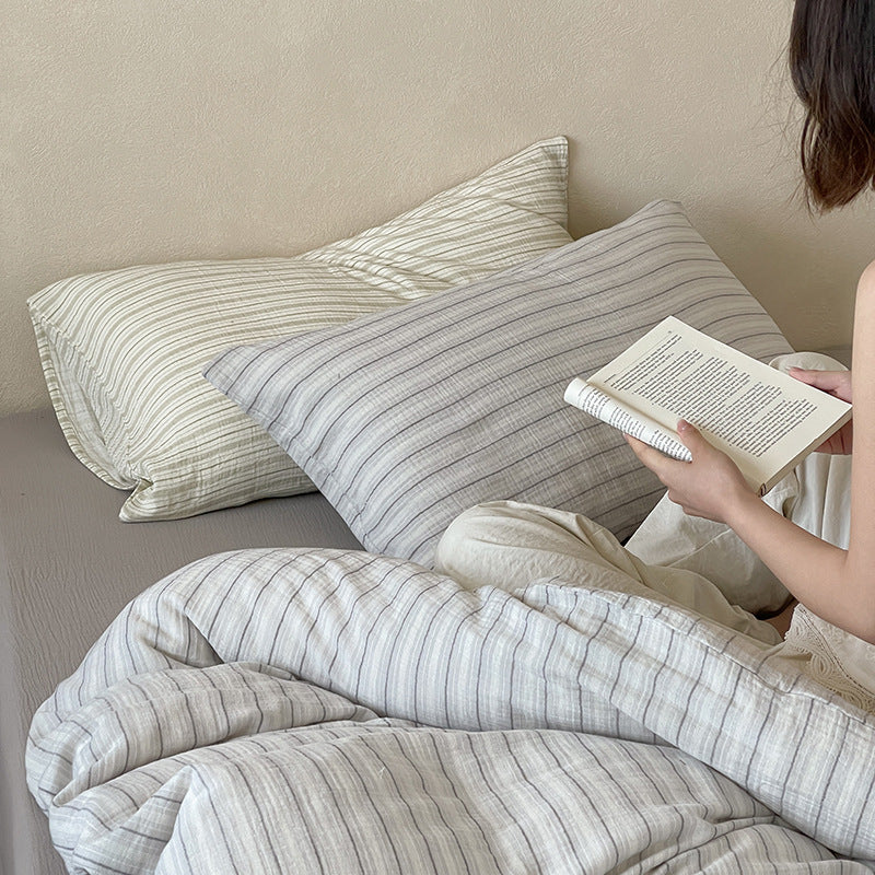 Halden Striped Cotton Double Gauze Bedding Set – grey striped pillows beside a person holding an open book - Roomden