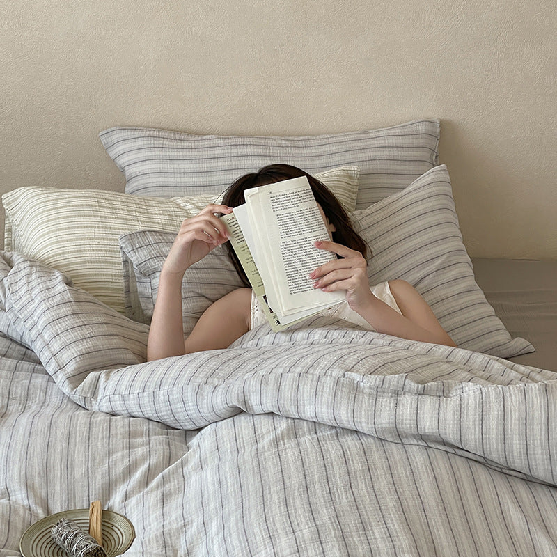 Halden Striped Cotton Double Gauze Bedding Set – a person reading under the grey striped duvet - Roomden