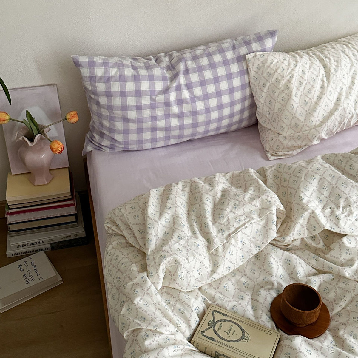 Ivory floral lattice cotton bedding with a lilac checked accent pillow, shown on a bed - Roomden