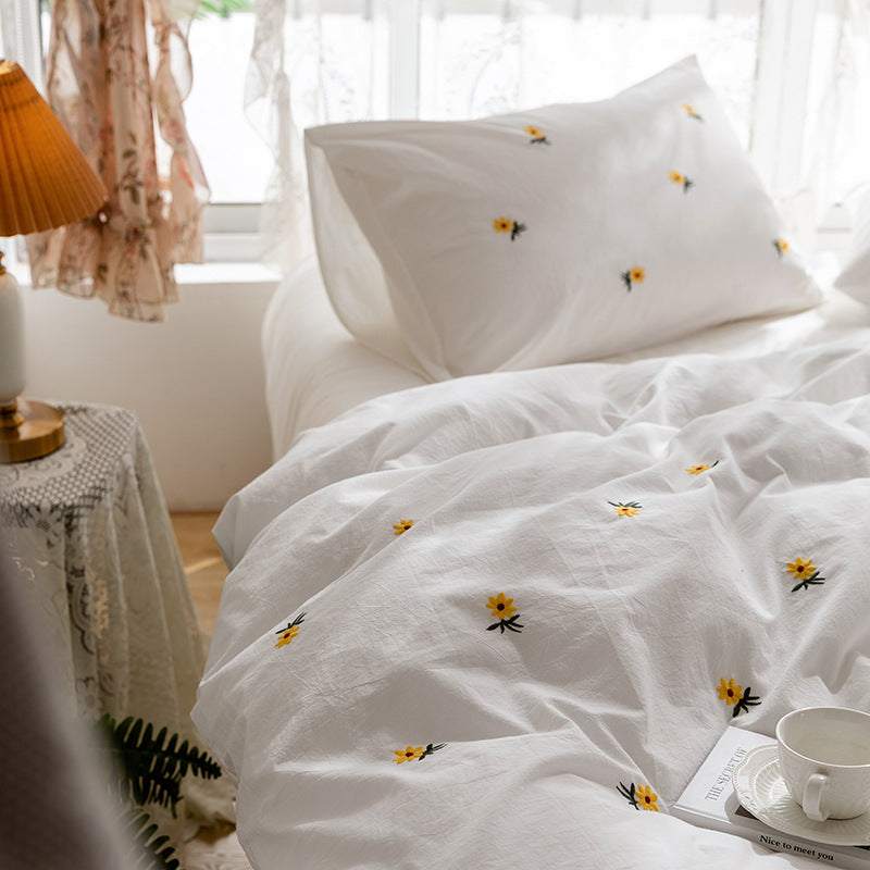 Daisy embroidered cotton bedding set – Upright embroidered pillow with the duvet folded below - Roomden