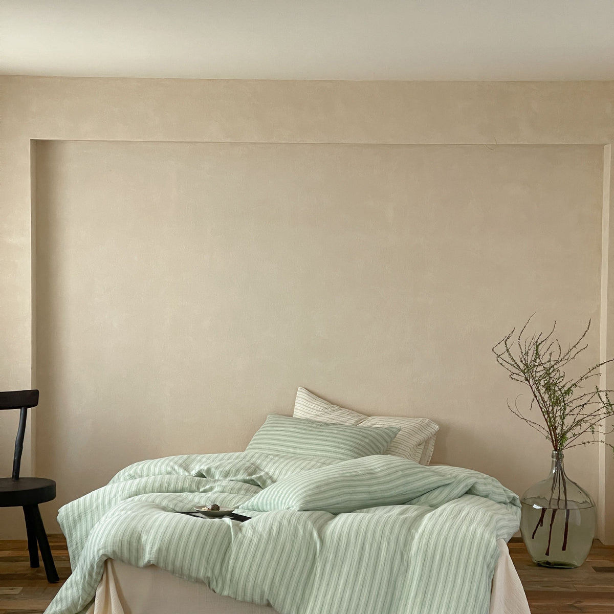 Halden Striped Cotton Double Gauze Bedding Set – sage striped bedding framed by a pale wall and dark chair - Roomden