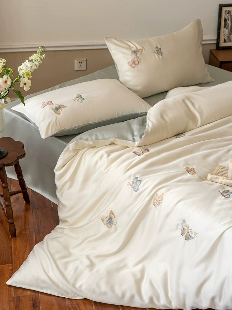 Butterfly embroidered lyocell bedding – Angled view of white embroidered pillows and duvet - Roomden