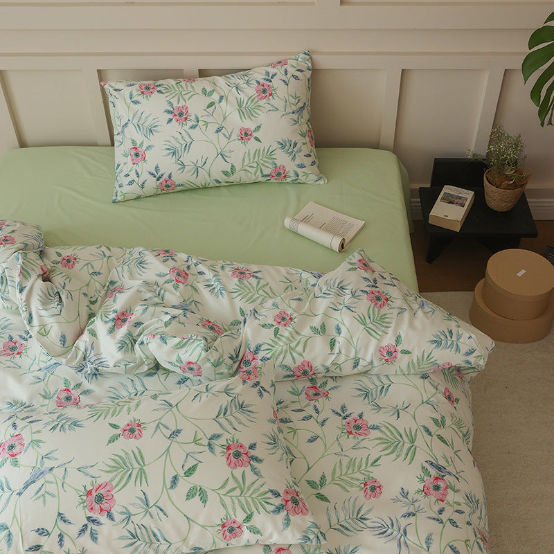 Ivory cotton bedding with pink flowers and blue-green leaves beside a pale green sheet - Roomden