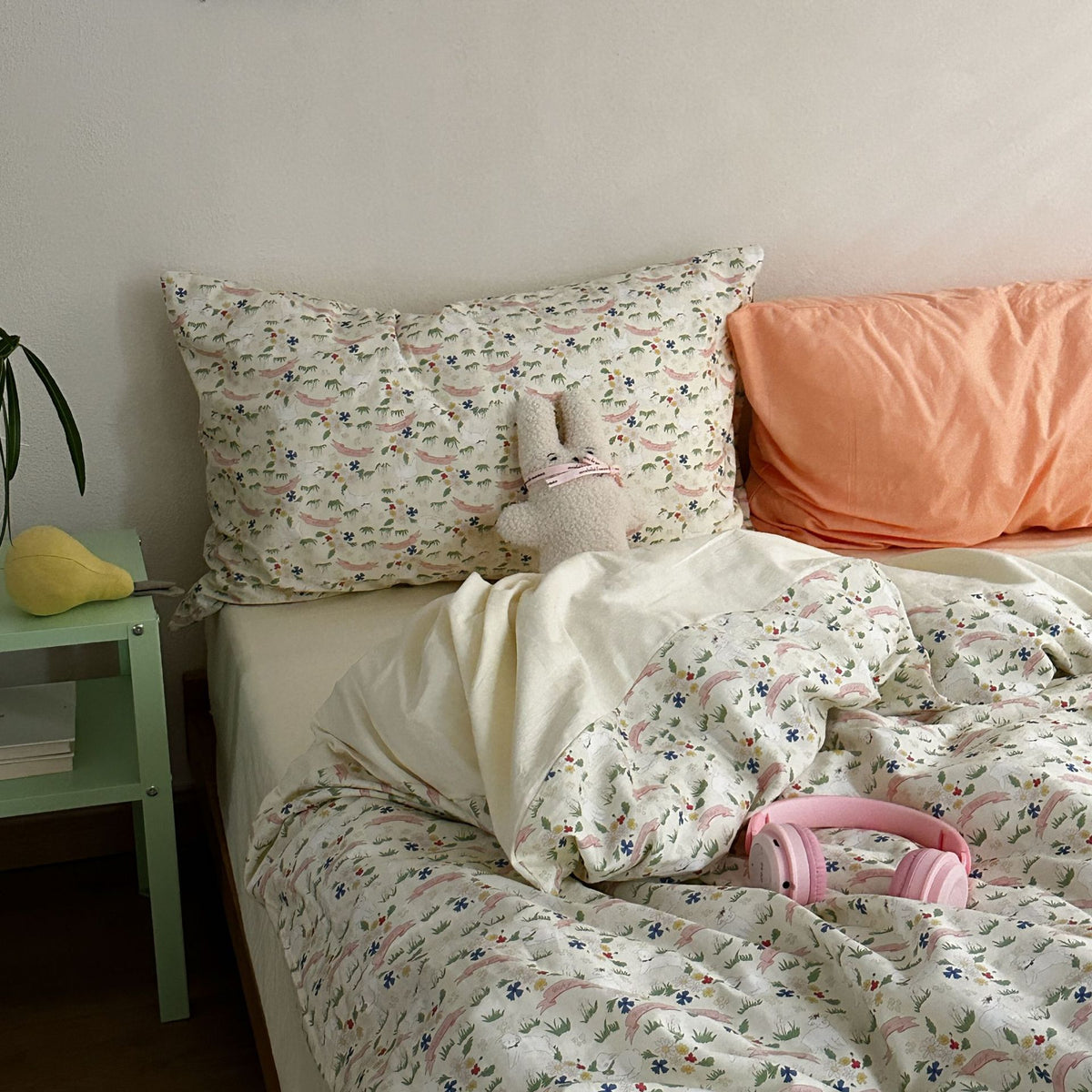 Colorful meadow floral cotton bedding with a peach accent pillow and cream reverse, shown on a bed - Roomden