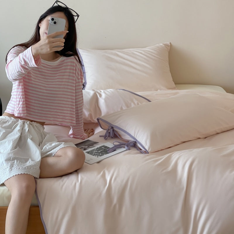 Contrast Tie-Knot Cotton Bedding Set – Pink with Purple Ties, seated person beside the pink-and-purple bedding - Roomden