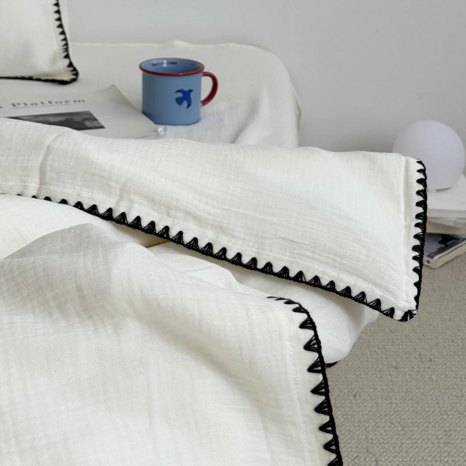 Close-up view of the corner of the duvet cover with black embroidered trim, showing the fabric's texture.