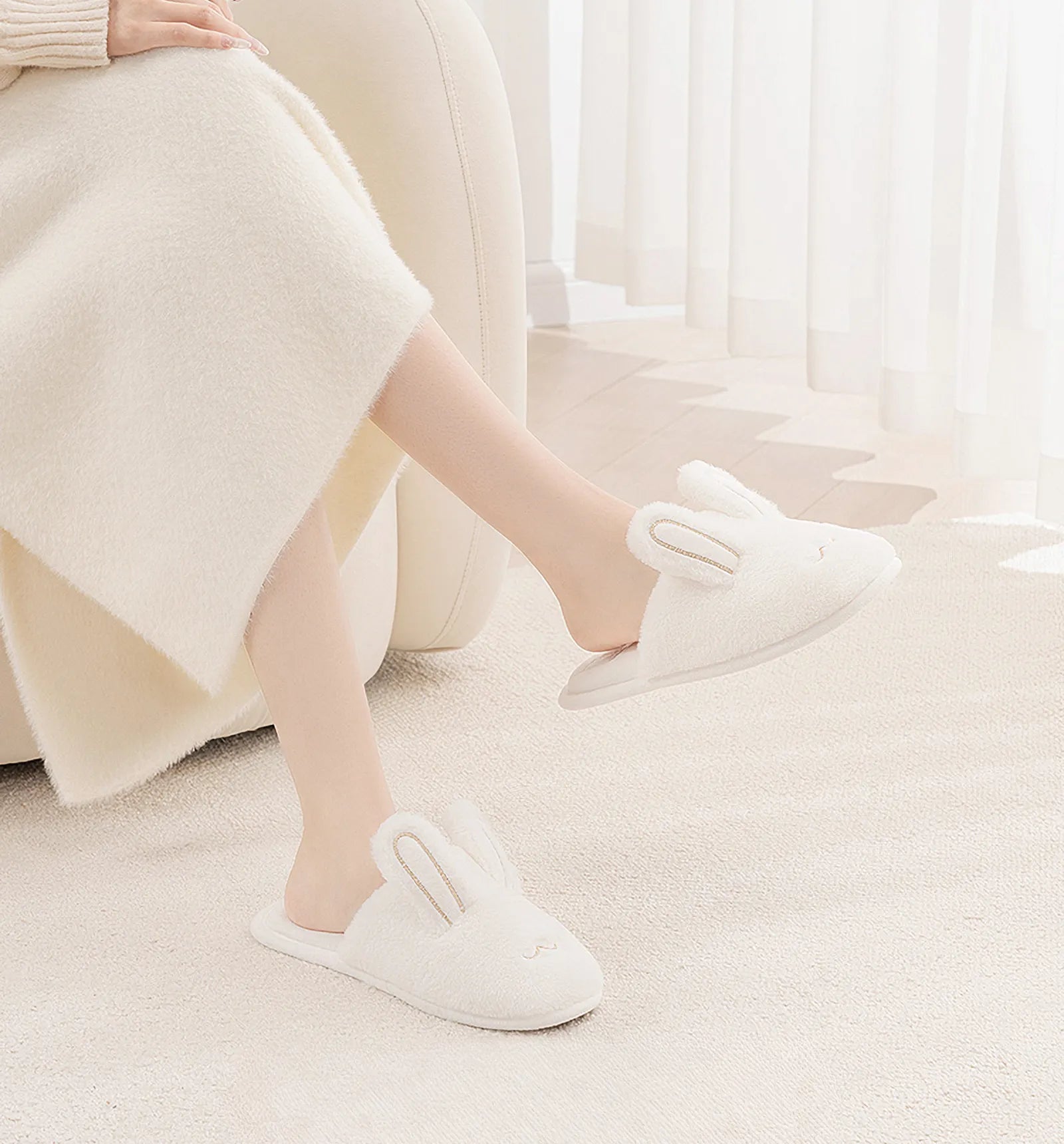 White bunny ear slippers on model legs relaxing on chair - RoomDen