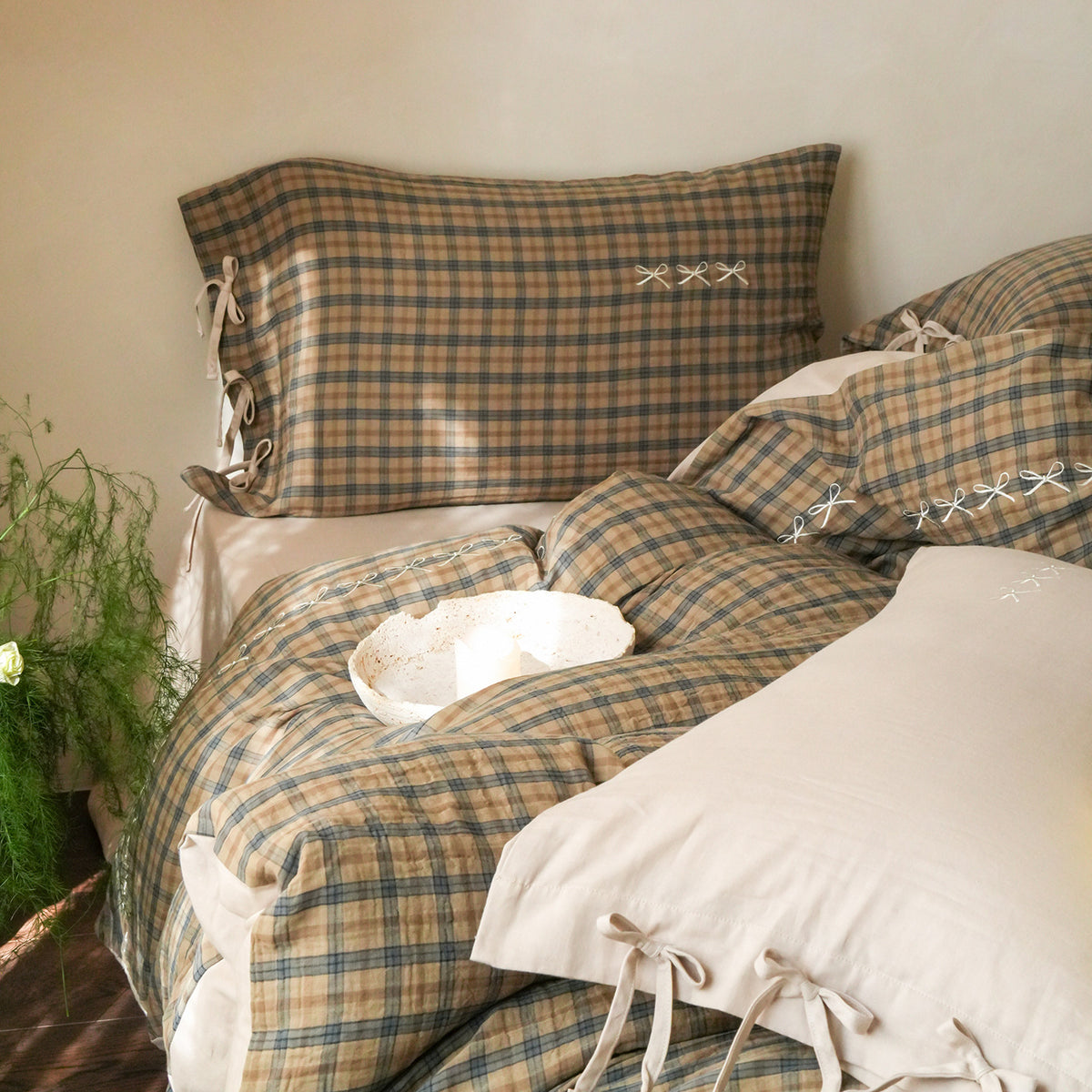 Brackenwood Checked Cotton Bedding Set – sage checked pillows and a folded duvet beside a plant - Roomden
