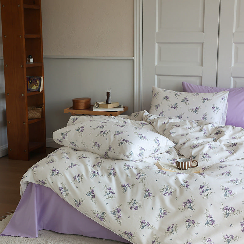 Ivory cotton bedding scattered with purple floral sprigs and lilac pillow styling - Roomden