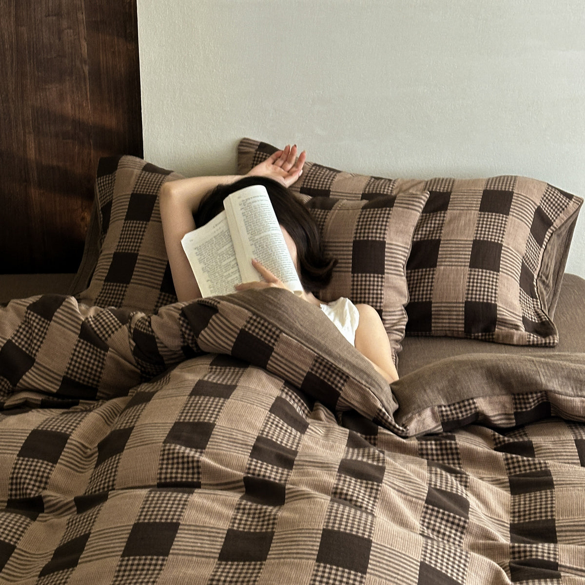 Gingham Jacquard Cotton Gauze Bedding Set – Cocoa Check, reader holding a checked pillow on the bed - Roomden