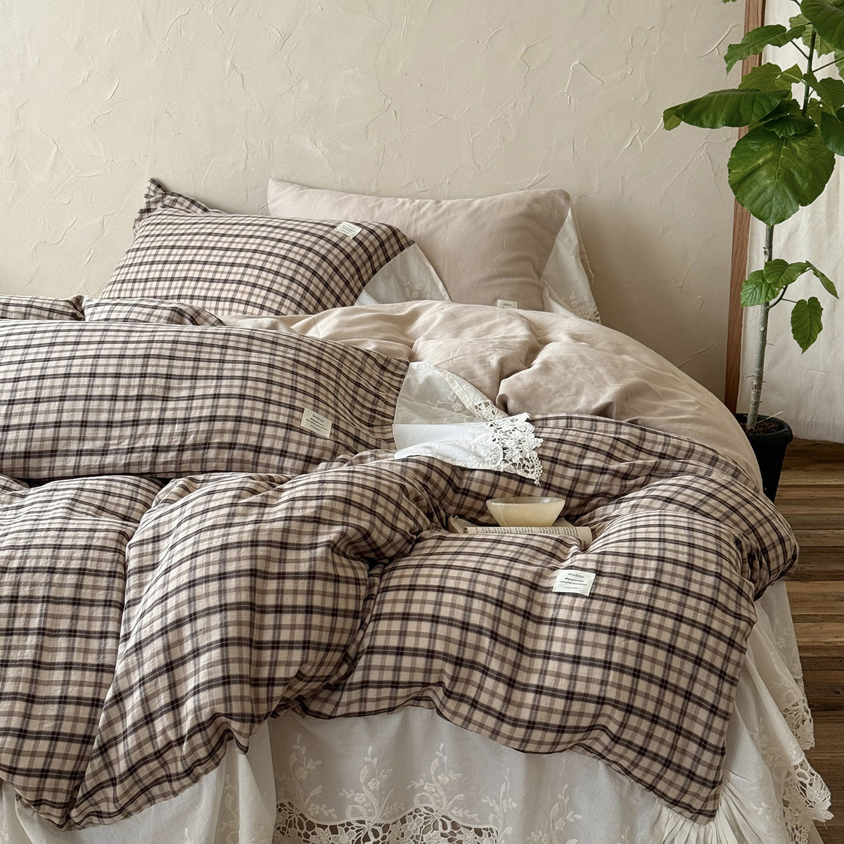 Checked Cotton Bedding Set with Bows and Lace – tea check bedding with broad white lace trim beside a leafy plant - Roomden