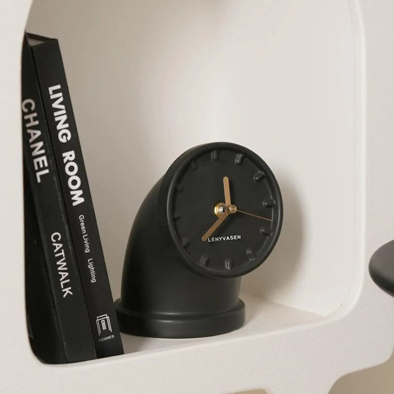 Matte black Industrial Pipe Ceramic Table Clock nestled on a white shelf next to designer books - RoomDen