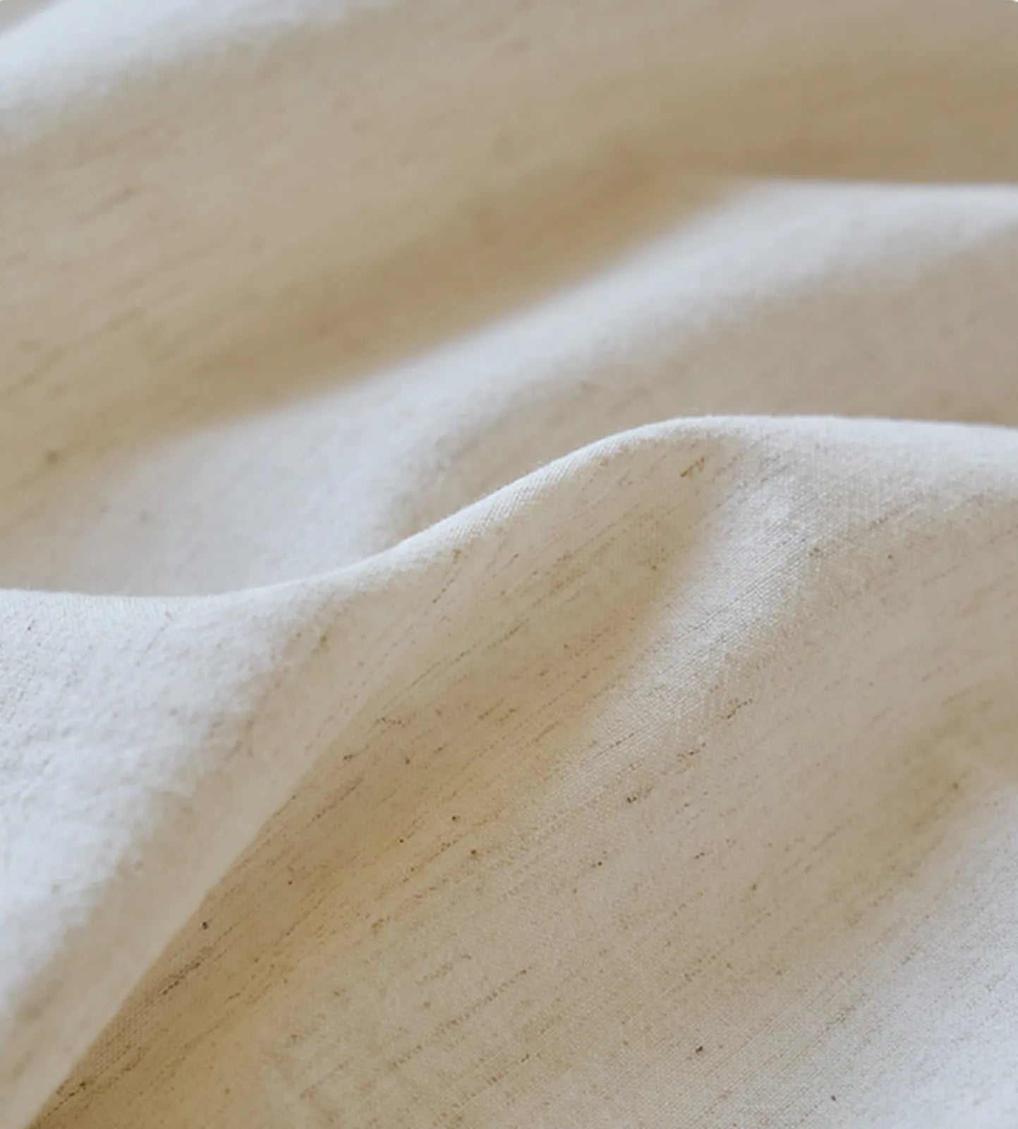 Extreme close-up of the natural, slubby texture of the cream-colored linen fabric - RoomDen.
