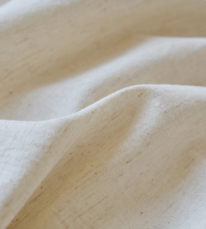 Extreme close-up of the natural, slubby texture of the cream-colored linen fabric - RoomDen.