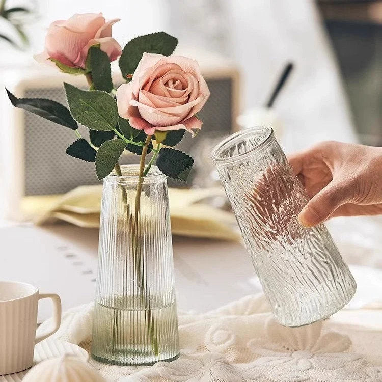 Hand holding the Large Bark Textured Glass Vase next to the Large Ribbed Glass Vase holding pink roses. - RoomDen