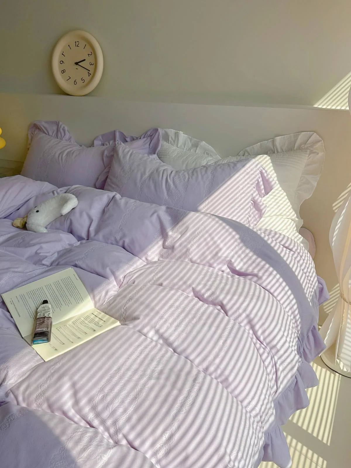 Lavender Coquette style bedding set with a minimalist clock on the headboard. - RoomDen