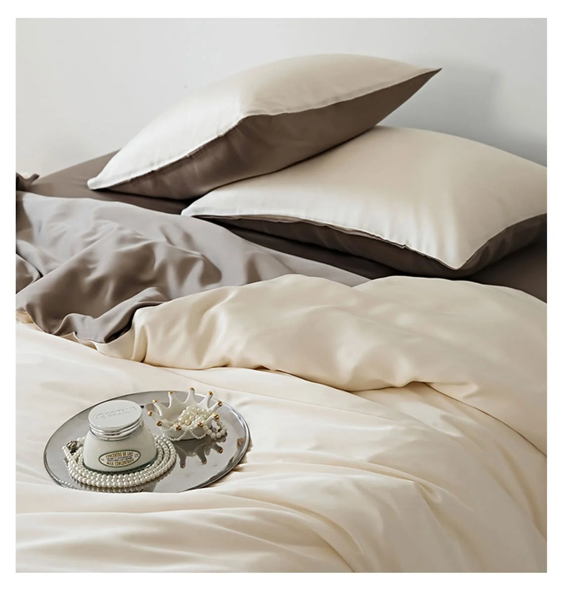 Lifestyle shot of the Cream & Taupe bedding with a decorative tray holding pearls and a candle.