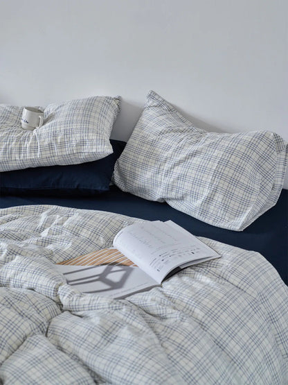 Navy Plaid Washed Cotton Bedding Set styled with an open book, showing the soft wrinkled texture - RoomDen