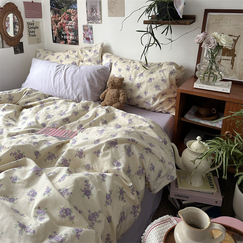 Cream and lilac floral cotton bedding set with purple flower clusters, styled beside a wooden bedside table - Roomden