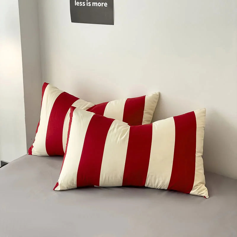 Close-up of two Red & Cream striped pillowcases from the Washed Cotton Bedding Set on a grey sheet - RoomDen