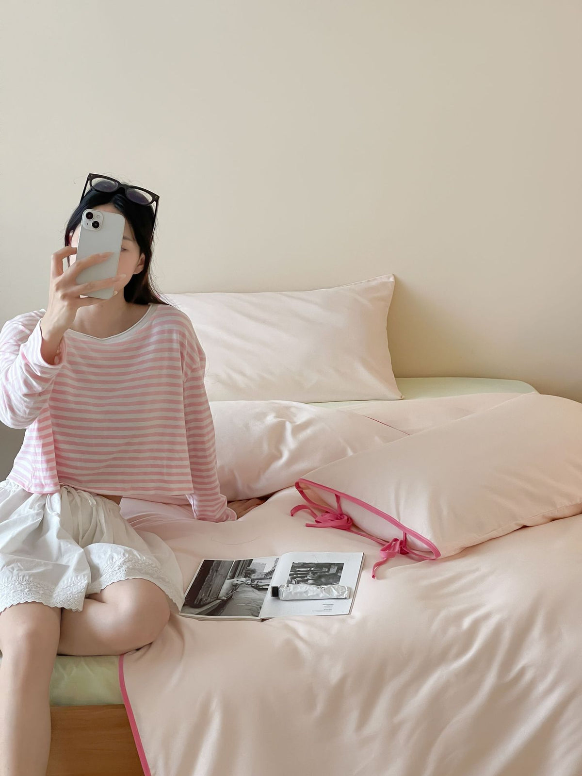 Contrast Tie-Knot Cotton Bedding Set – Pink with Barbie Pink Ties, seated person beside the pale pink bedding - Roomden