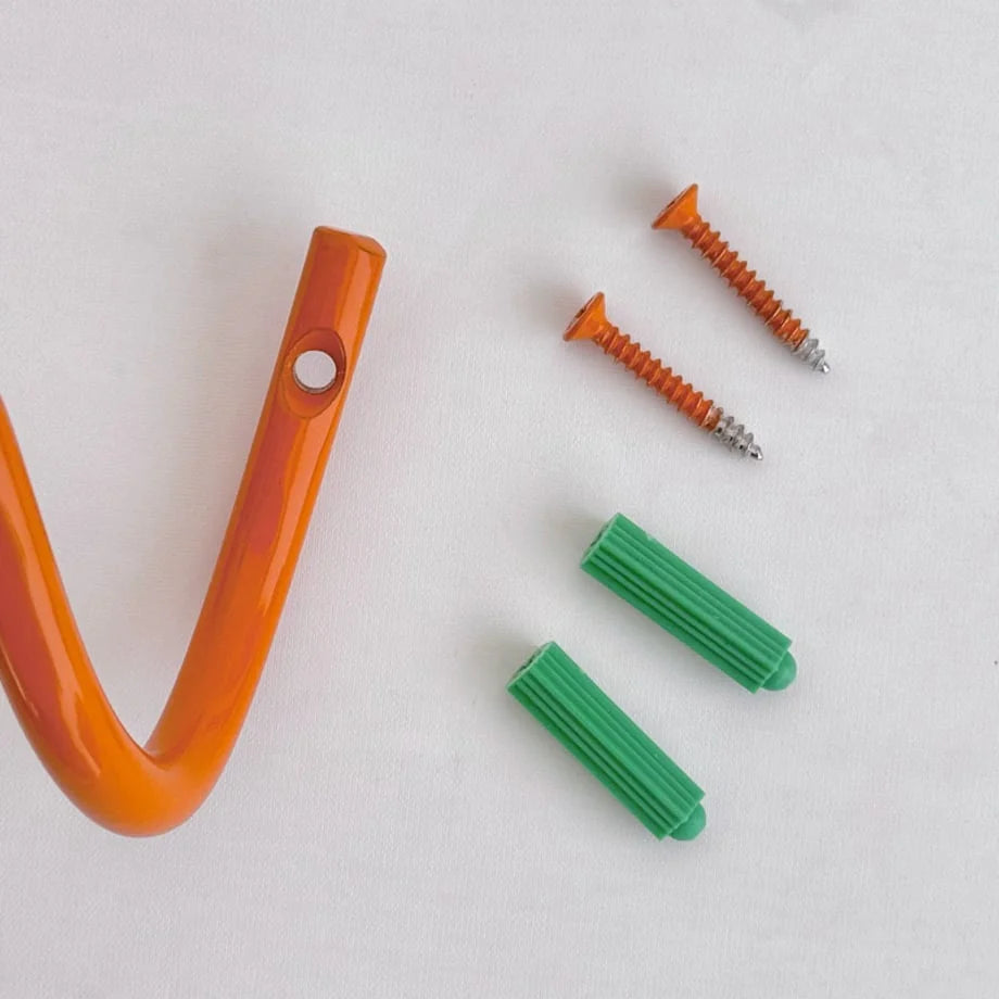 Close-up of the installation hardware, including orange screws and green wall anchors, for the Wavy Coil Metal Wall Hook. - RoomDen