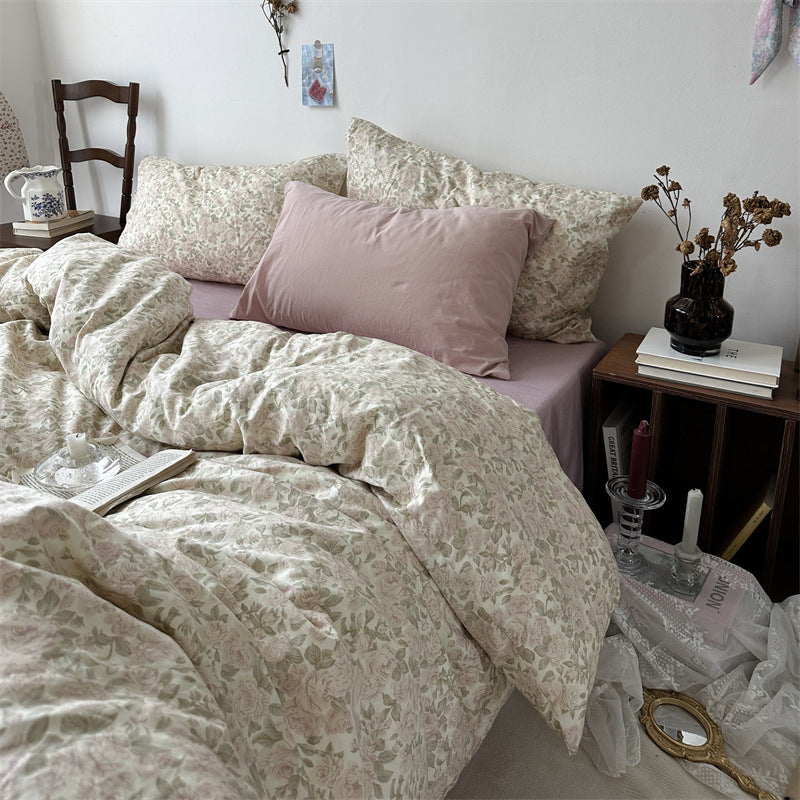 Ivory blush rose cotton bedding set with pale pink flowers and sage green leaves, shown in soft bedroom light - Roomden
