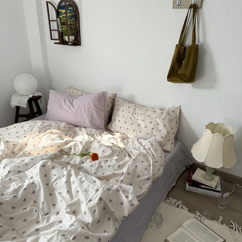 Ivory rosebud stripe cotton bedding with tiny pink-purple flowers over fine pale stripes, styled on a bed - Roomden