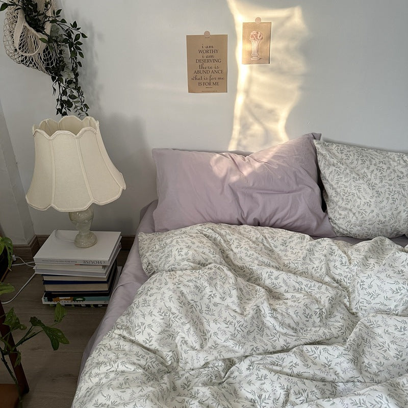 Ivory leaf print cotton bedding – gray-green sprigs with lilac pillow styling in a sunlit bedroom - Roomden