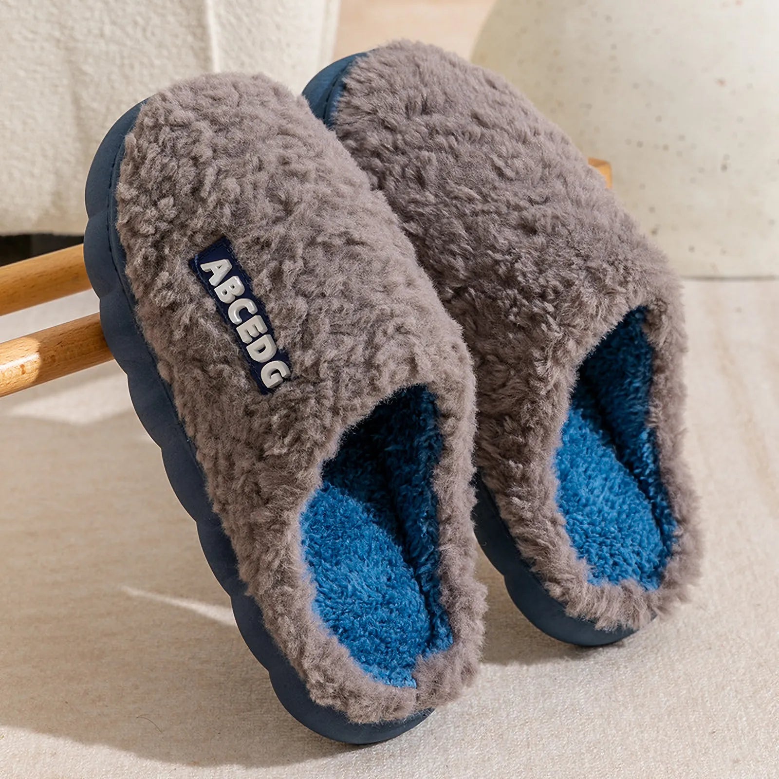 Grey upper with blue sole plush house slippers hanging on wooden rack - RoomDen