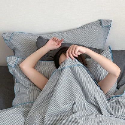 A person playfully hiding under the Dark Grey & Blue Pinstripe Washed Cotton Duvet Cover.