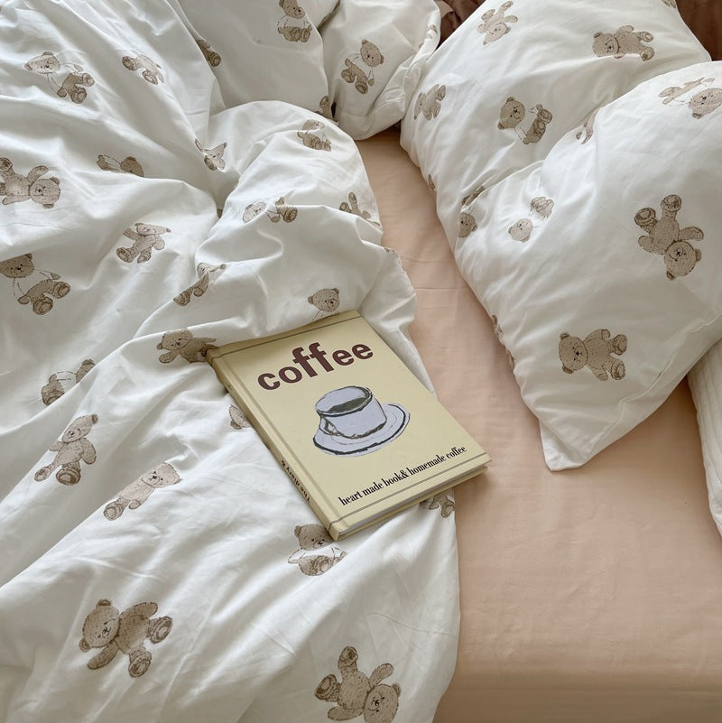 Close view of brown teddy bear print on ivory cotton bedding with a beige sheet - Roomden