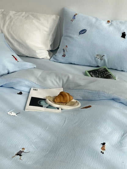 The sky blue embroidered bedding set styled with a croissant and books, creating a relaxed morning vibe.