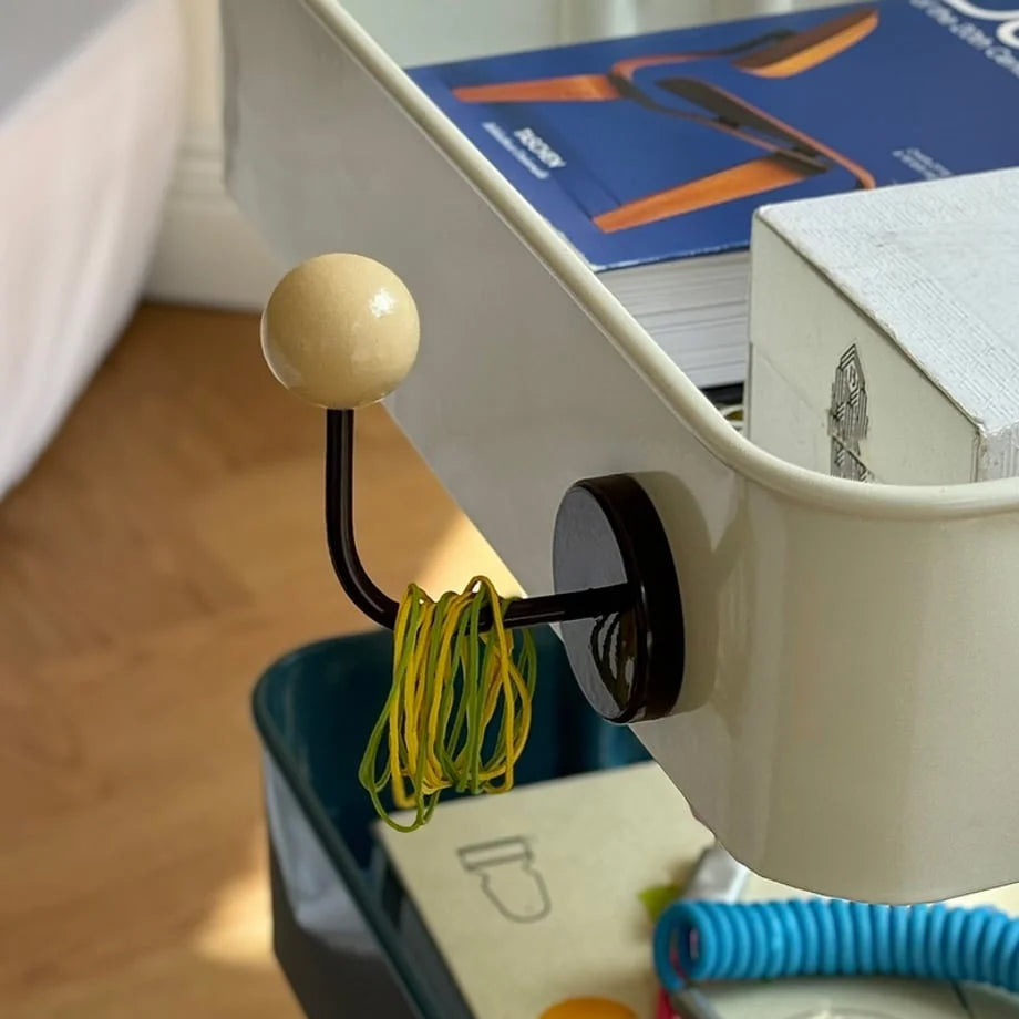 The Cream & Brown Metal Hook holding yellow hair ties on the side of a white cart - RoomDen.