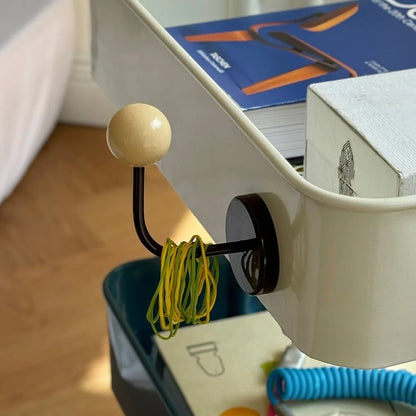 The Cream & Brown Metal Hook holding yellow hair ties on the side of a white cart - RoomDen.