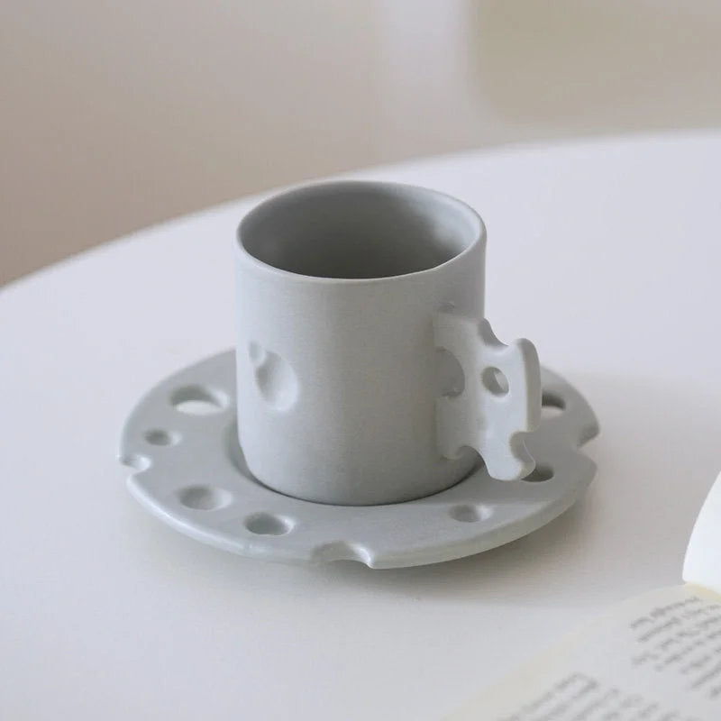 The Cheese Ceramic Mug & Saucer Set in Light Grey on a clean white surface. - RoomDen