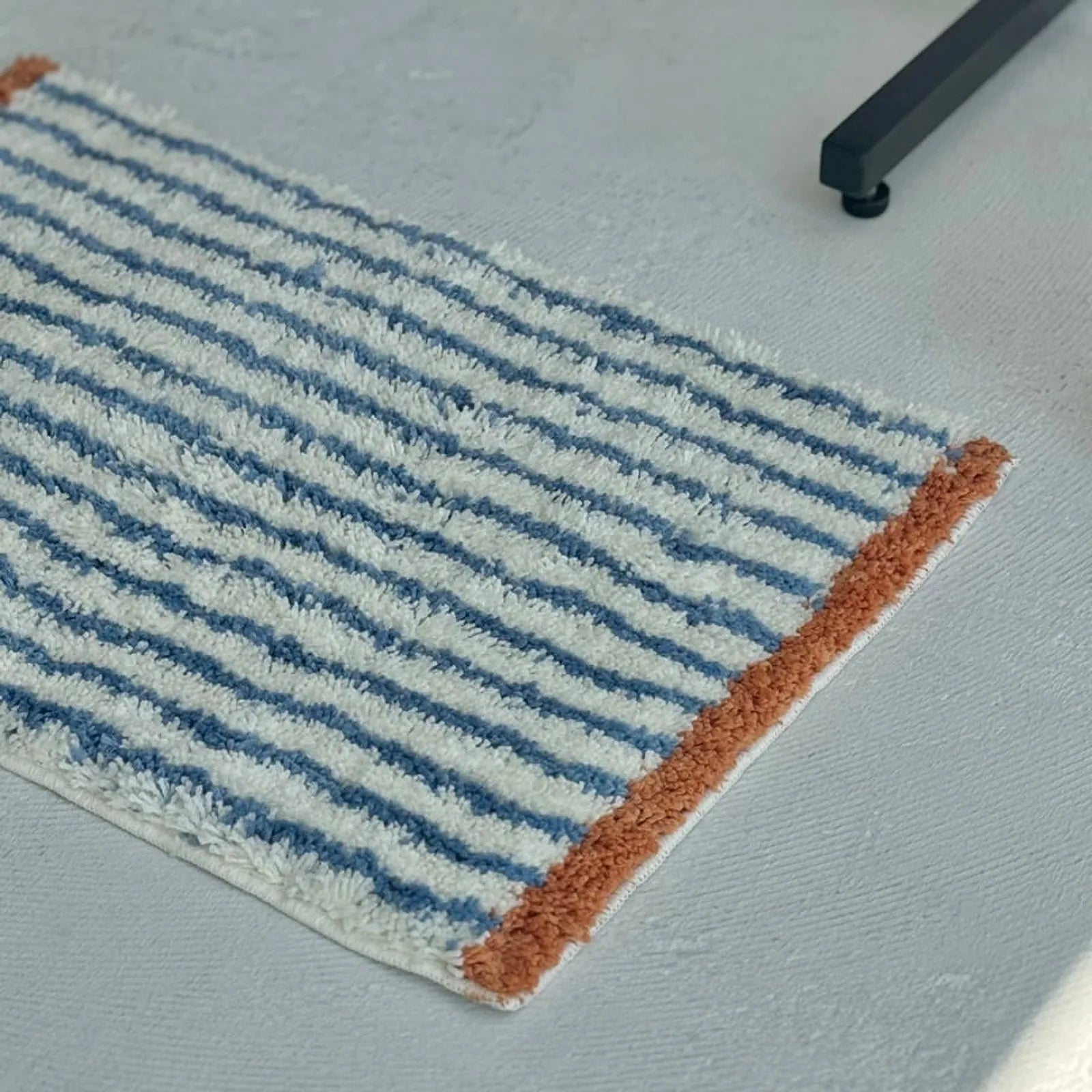 Close up perspective of Brown & Blue Striped rug edge and soft fibers