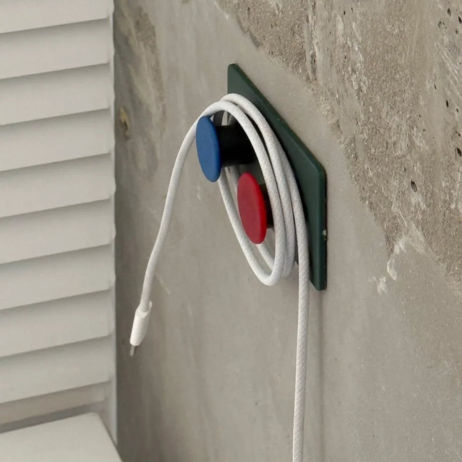 Green Colorblock Decorative Hook used as a cable organizer, neatly holding a white cord against a concrete wall - RoomDen.