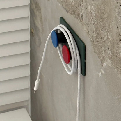 Green Colorblock Decorative Hook used as a cable organizer, neatly holding a white cord against a concrete wall - RoomDen.