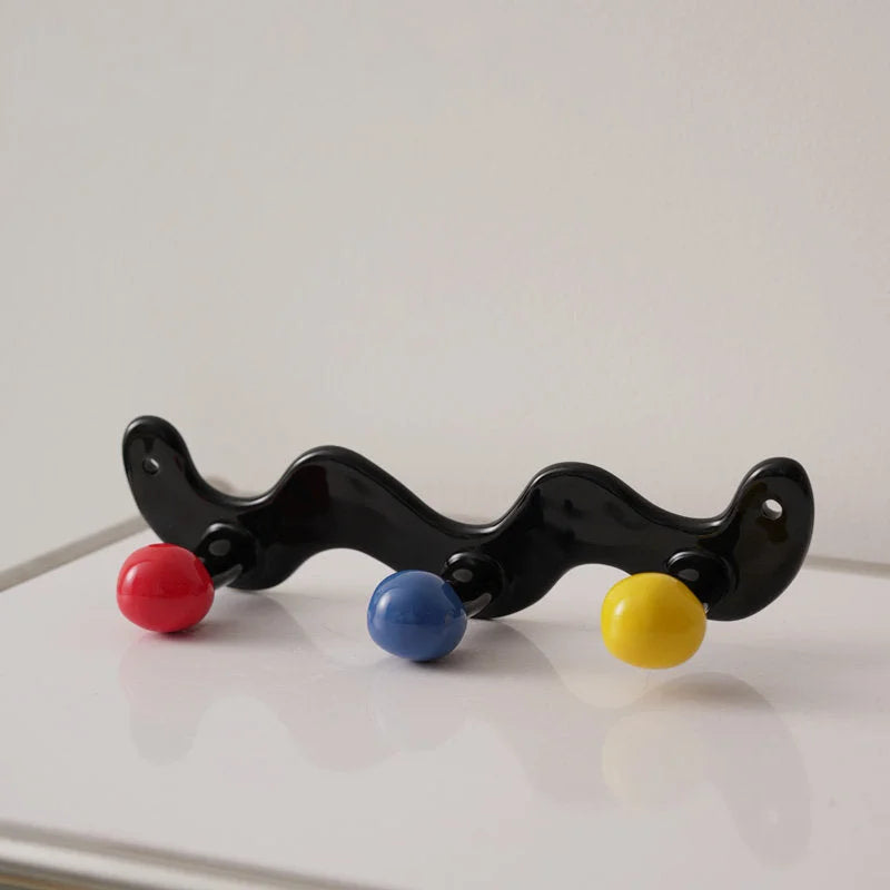 Three-hook wavy black ceramic wall hook with red, blue, and yellow balls.