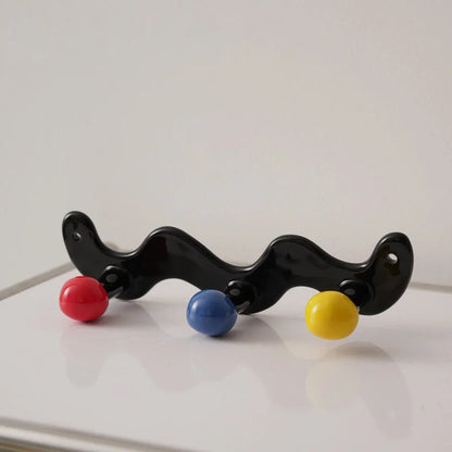 Three-hook wavy black ceramic wall hook with red, blue, and yellow balls.