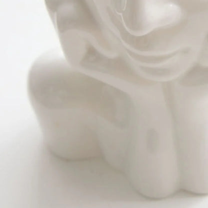 Close-up detail of the smooth, glossy finish on the white resin face vase - RoomDen.